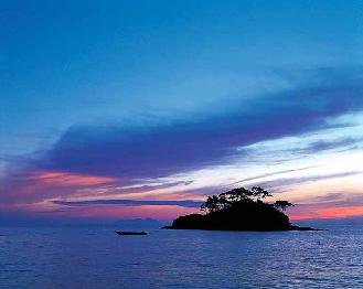 Island in silhouette with deep blue sea and pink, white and blue sky