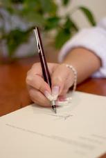 hand with pen writing on paper